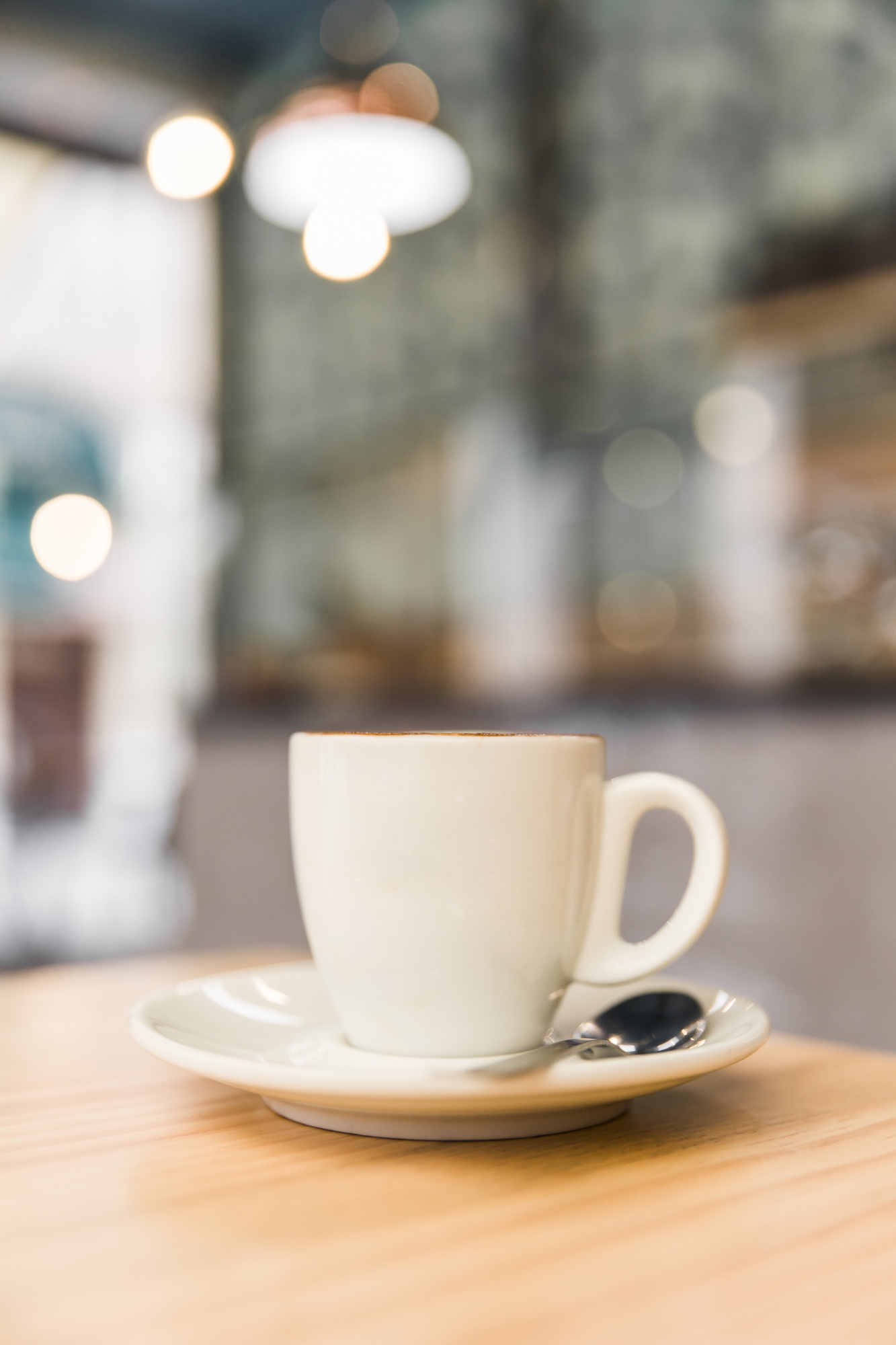 Xícara branca de café sobre mesa de madeira clara